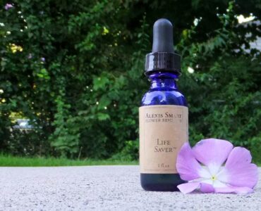 Alexis Smart Remedy Photo with blue glass bottle with brown label sitting next to a lavender colored flower