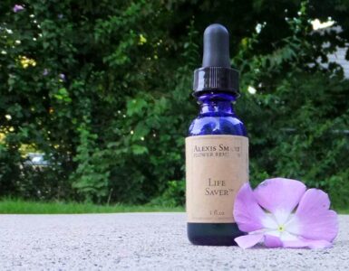 Alexis Smart Remedy Photo with blue glass bottle with brown label sitting next to a lavender colored flower