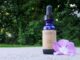 Alexis Smart Remedy Photo with blue glass bottle with brown label sitting next to a lavender colored flower